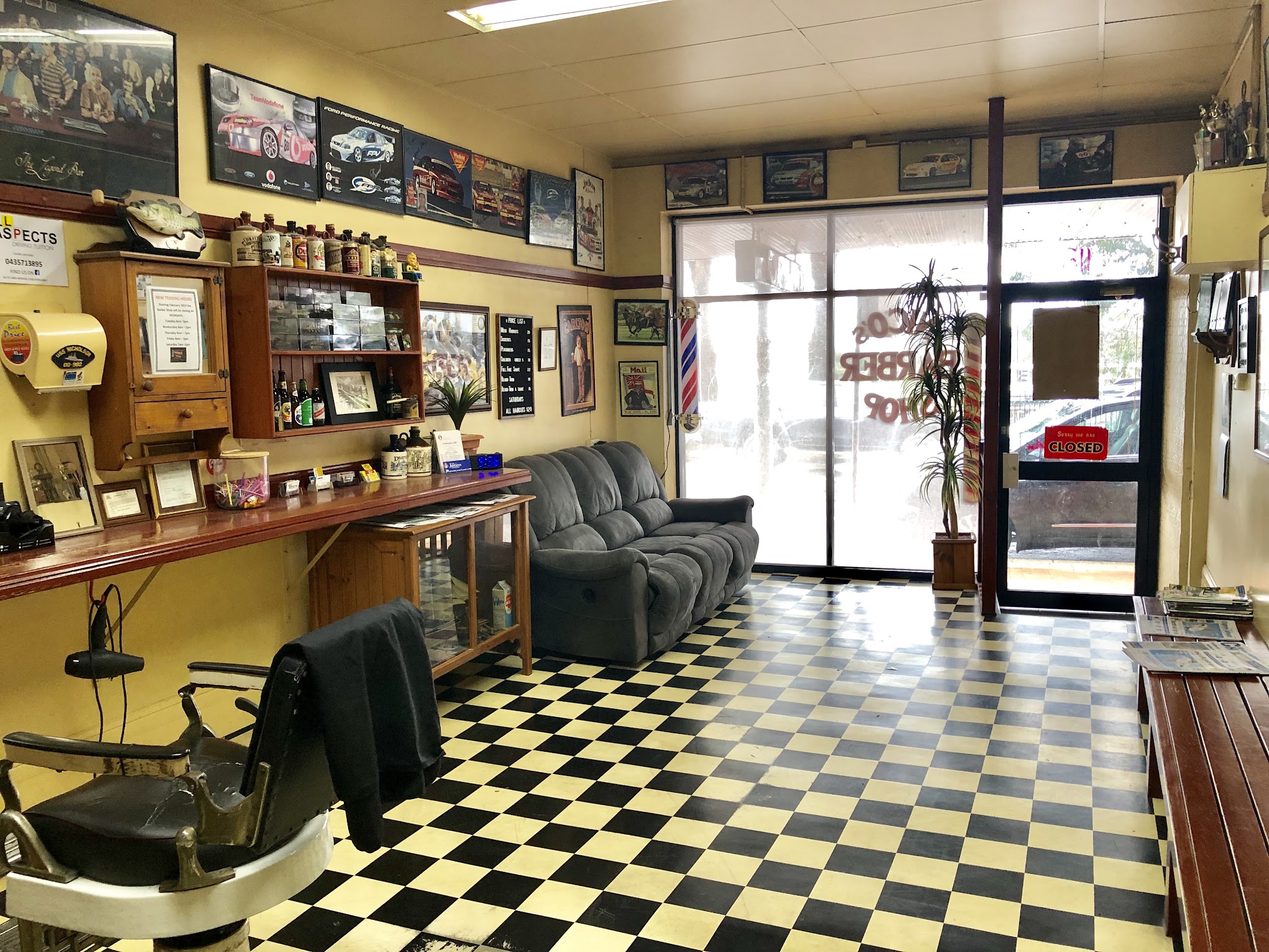 The waiting area at Nico's Barber Shop, with a couch and the shop name lettered on the window