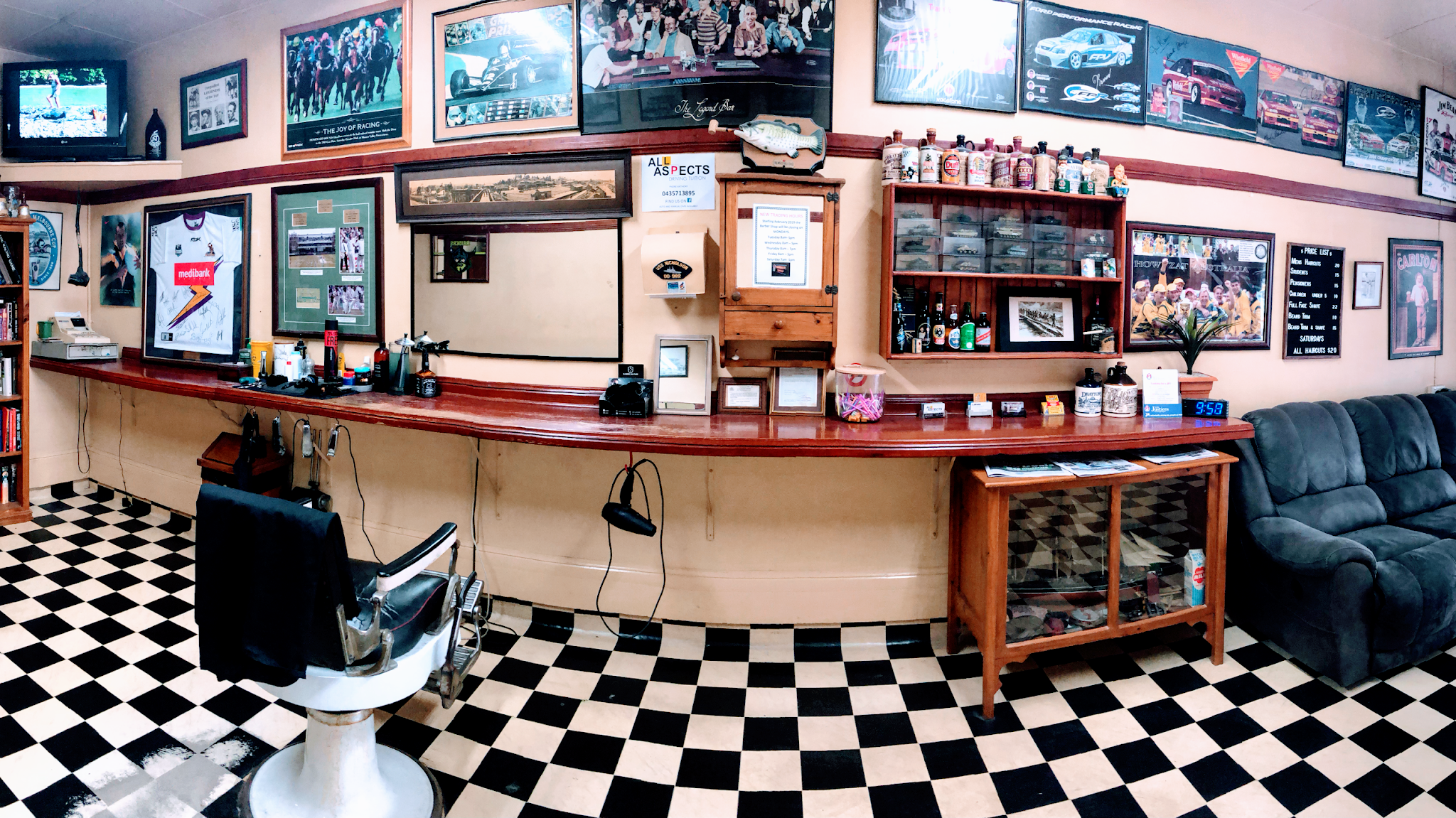Wide view inside Nico's Barber Shop: timber counter, checkerboard floor, and a wall of framed sporting memorabilia
